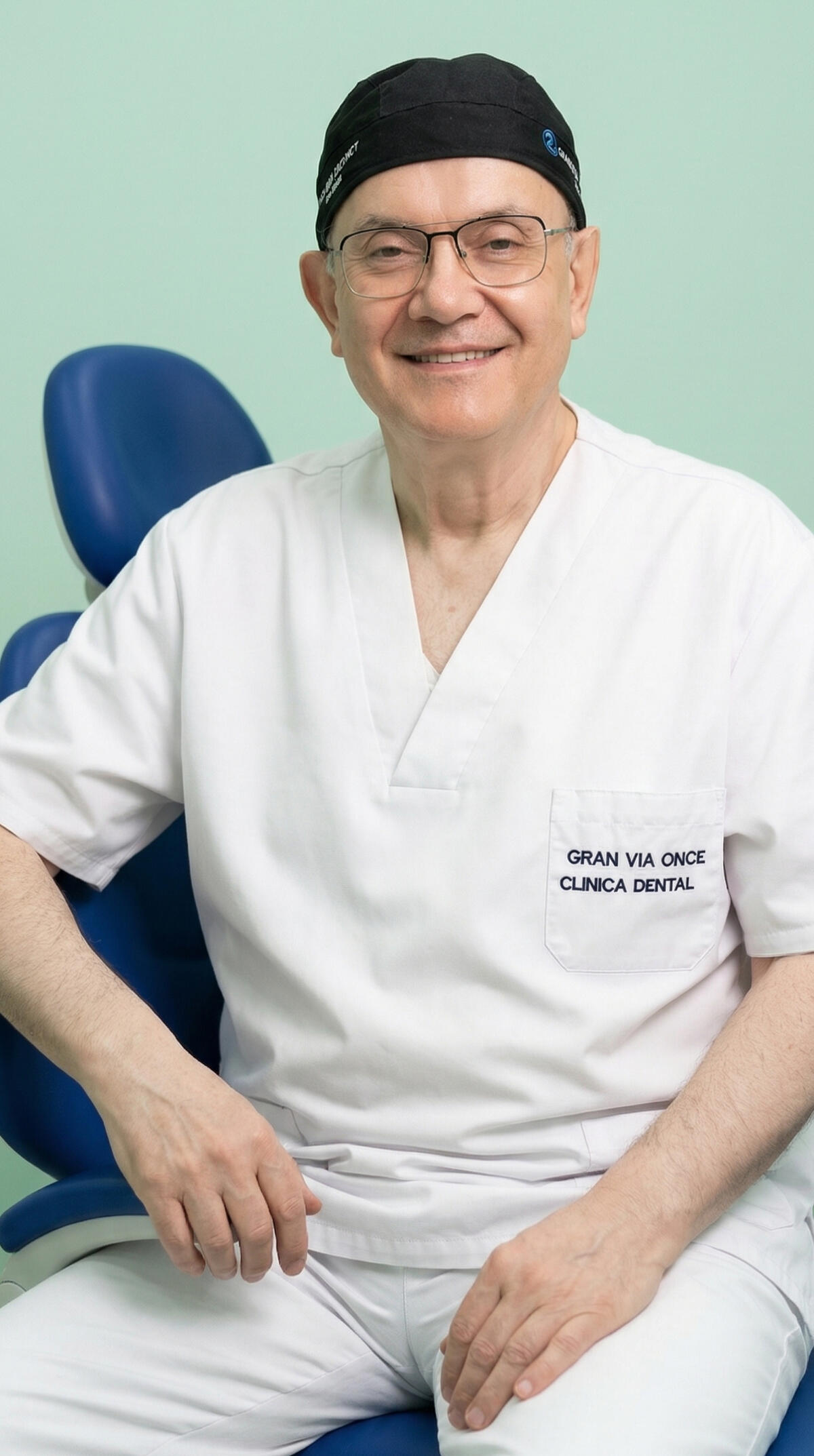 Fotografía de retrato de un dentista con décadas de experiencia mirando hacia la cámara